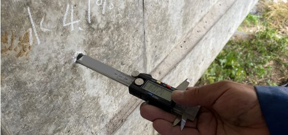 ノギスで中性化深さを計測している状況